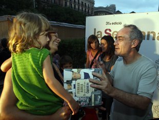 Imatge del cuiner Ferran Adrià atenent una petita lectora a la Setmana del Llibre en Català.
